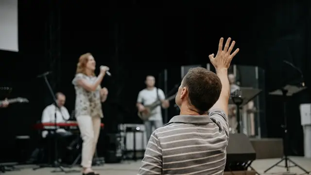 man wearing grey stripe polo shirt raising his right hand