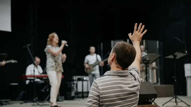 man wearing grey stripe polo shirt raising his right hand